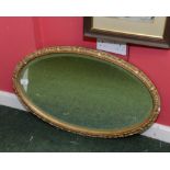 An oval gilt framed mirror with conforming bevelled plate