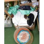A box of curtain and table linens, fur tippets, military cap, studio glass bowl etc