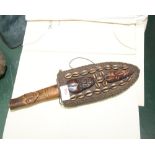 A tribal dagger, the wooden hilt carved with a mask in a sheath, applied with cowrie shells and