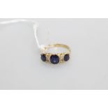 An Edwardian sapphire and diamond ring, the three oval-cut graduated sapphires spaced by two pairs