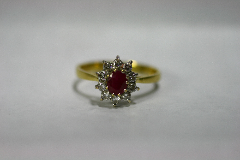 An 18ct. gold ring set oval ruby within a border of small diamonds.