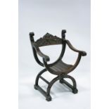 An Italian carved walnut Savonarola-type elbow chair decorated with grotesque masks & leaf-