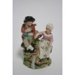 An early 19th century Staffordshire pottery group of male & female musicians, he playing a pipe, she