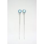 A pair of long hat pins with hinged octagonal guilloch enamel pearl-grey & turquoise terminals; in