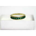 An 18K half-hoop ring set nine round-cut emeralds.