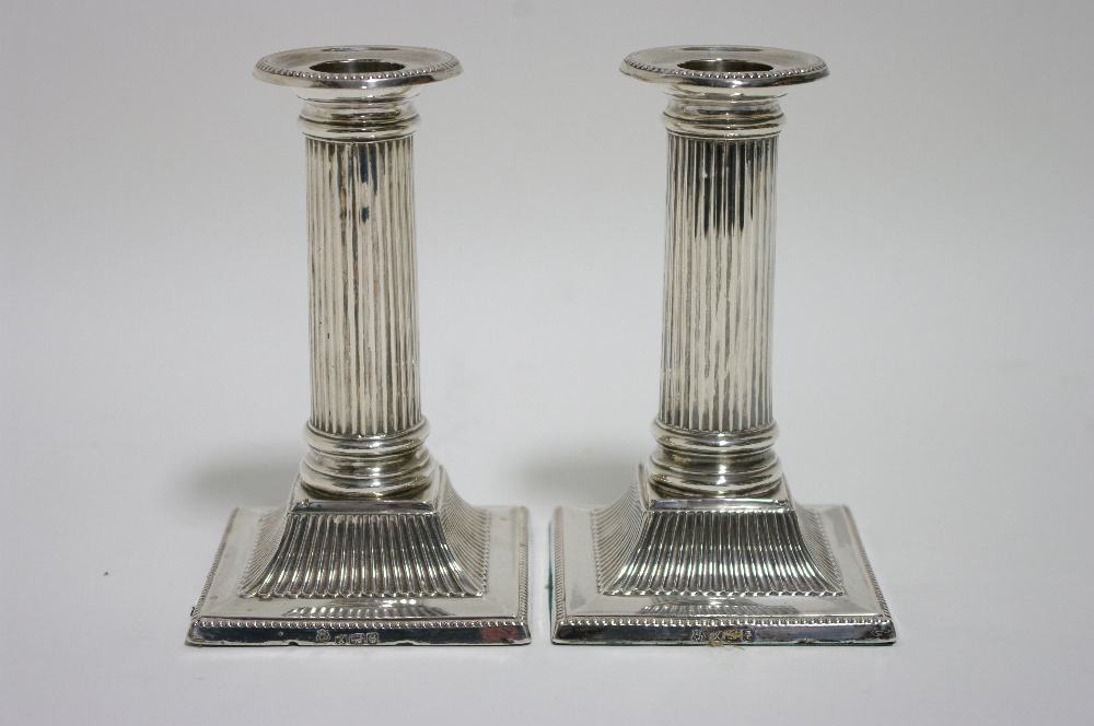 A pair of late Victorian desk candlesticks with round fluted columns, each on square base with