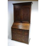 An 18th century oak bureau bookcase with dentil & blind-fret friezes to the cornice, fitted three