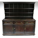 AN 18th century OAK DRESSER with open tiered shelves above, fitted three frieze drawers with applied