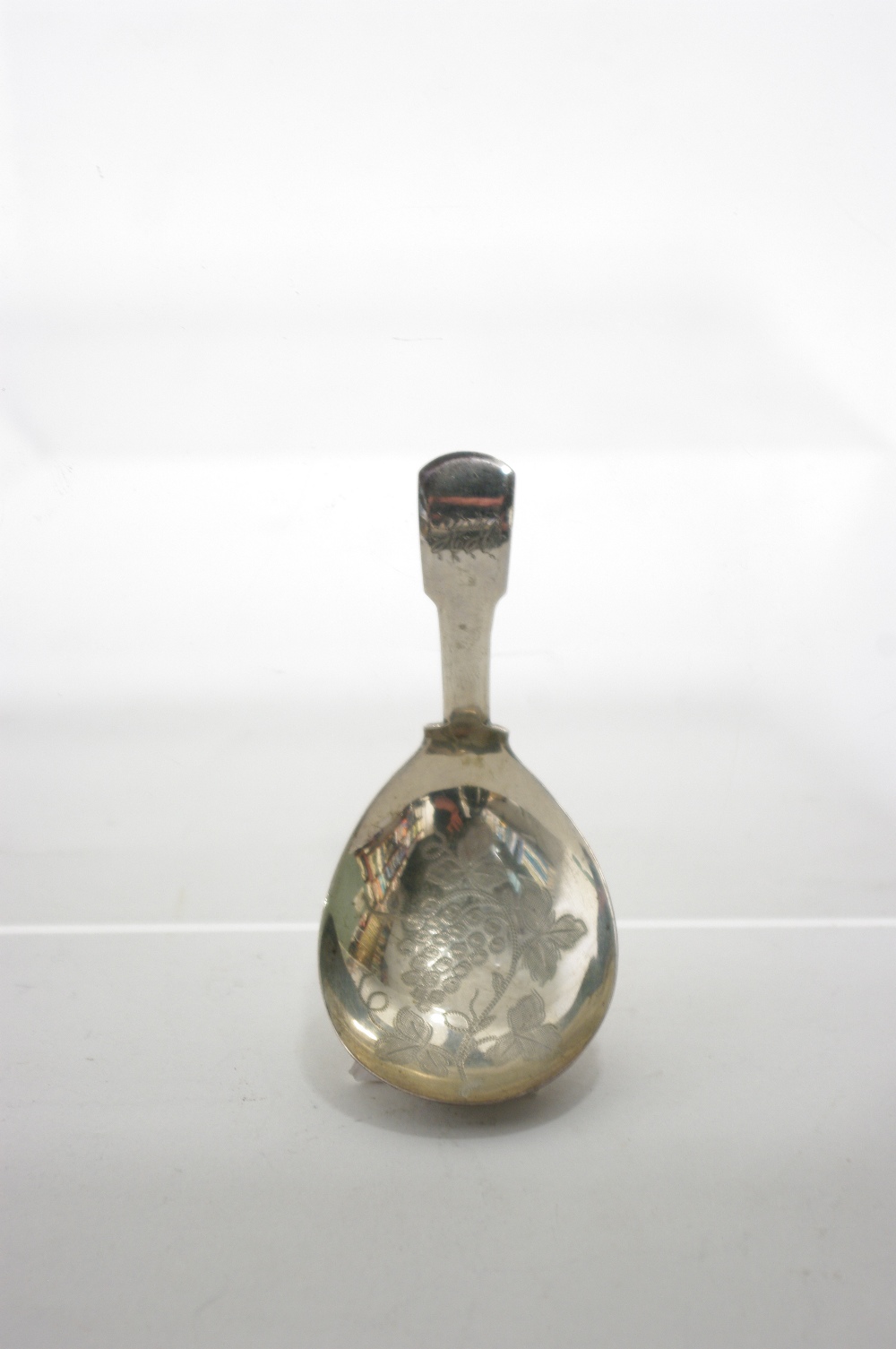 A George III Fiddle pattern caddy spoon, the wide oval bowl with pricked decoration of leaves &