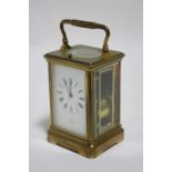 A French brass carriage clock with repeating movement striking on a coiled gong, the white enamel