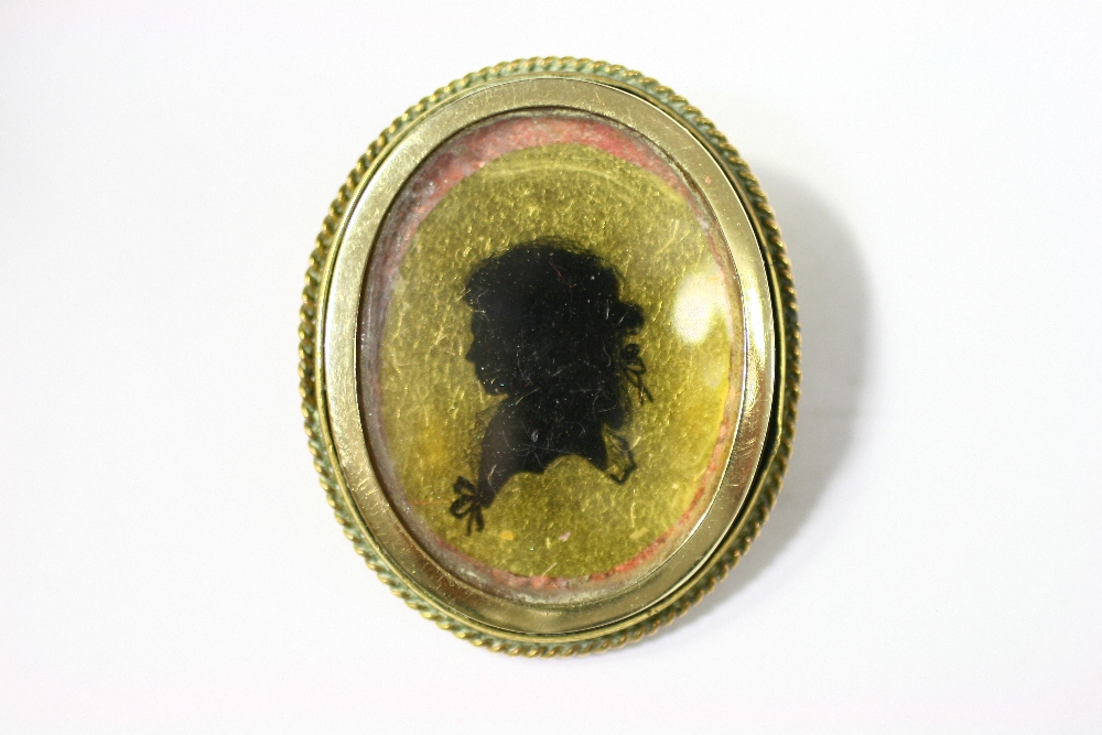 A 19th century gilt-metal oval brooch with silhouette portrait of a young lady to the centre.