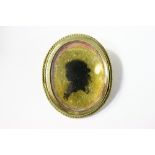 A 19th century gilt-metal oval brooch with silhouette portrait of a young lady to the centre.