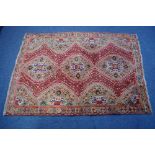 A Persian rug of crimson ground, with row of three central lozenges, & all-over multi-coloured
