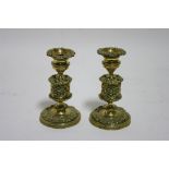 A pair of early 19th century brass dwarf candlesticks with all-over embossed floral decoration, on