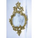 A shaped oval wall mirror in gilt composition pierced rococo-style frame decorated with flowers &