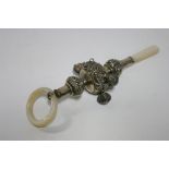 An Edwardian baby’s rattle with embossed scroll decoration, four (of six) pendant bells, mother-of-