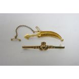 A 9ct gold Claddagh brooch; & a yellow metal eastern dagger brooch.