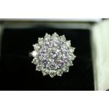 A DIAMOND THREE-TIER CLUSTER RING, the brilliant-cut centre stone weighing 0.69 carat, surrounded by