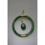 A green jade stiff-hinged bangle with gilt-metal mounts; & a similar small oval pendant.