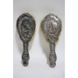 A pair of Edwardian hair brushes, the silver-mounted backs embossed with children amongst fox-gloves