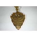 An Edwardian 9ct gold shield-shaped pendant fob with engraved inscription: “Dartmouth 100 Guinea