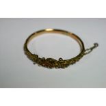 An Edwardian 9ct gold stiff-hinged bangle with applied bead & scroll decoration, & set two small