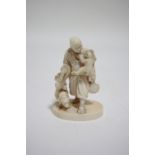 A Japanese carved ivory okimono group of an itinerant street performer carrying a small drum, a