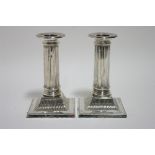 A pair of late Victorian desk candlesticks with round fluted columns, each on square base with