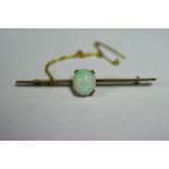 A 9ct gold “Knife-edge” bar brooch set oval cabochon opal; with safety chain, 2¼" long, in