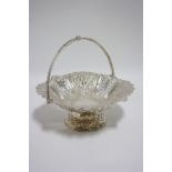 An Edwardian circular cake basket with swing handle, decorated with alternating pierced & fruit-