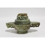 A Chinese green & russet jade censer of round form with wide dragon-mask side handles, & coiled