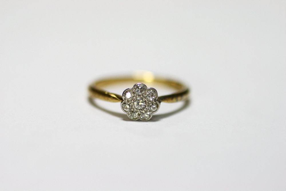 An 18ct. gold & platinum ring set cluster of small diamonds; & a similar ring set row of five