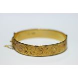 A 9ct. gold stiff hinged bangle with engraved decoration to one half.  (37 gm).