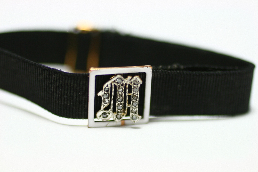 A gold, white enamel, & woven black silk adjustable bracelet, the square open-work panel centred