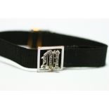 A gold, white enamel, & woven black silk adjustable bracelet, the square open-work panel centred