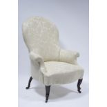 An early Victorian upholstered armchair with tall rounded back, scroll arms, wide sprung seat & on