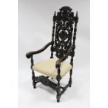 A Carolean-style large elbow chair with carved & pierced tall foliate back, curved arms, padded