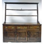 AN 18th century OAK DRESSER with open shelves above, the base fitted three frieze drawers above