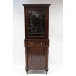 A mahogany narrow display cabinet enclosed by a glazed door above a frieze drawer, a panel door