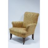 A late Victorian upholstered armchair with square back, sprung seat, & on short turned walnut legs