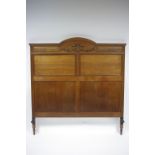 An early 20th century oak double bedstead, the tall head-board & foot with applied carved floral