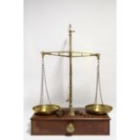 An early 20th century large set of brass beam scales mounted on mahogany box base, 20½" wide,