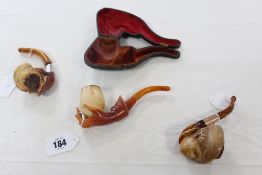 A Meerschaum pipe, the bowl carved in the form of a hand, with amber stem; together with two other