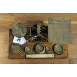 An early 20th century brass postal scale mounted on oak plinth base with bun feet, and with five