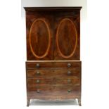 An early 19th century figured mahogany linen press enclosed by a pair of panel doors centred by