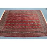 A Bokhara pattern carpet of crimson ground, with six rows of twenty six guhls; 11ft x 8ft 5".