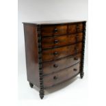 An early 19th century figured mahogany bow-front chest with protruding ring-turned pilasters, fitted