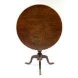 A late 18th century oak tripod table, the circular tilt top with birdcage support, on baluster