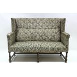 An upholstered wing-back sofa on oak baluster legs with plain stretchers; 57" wide. (requires re-