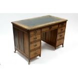 A late Victorian oak kneehole desk inset green tooled leather top, fitted nine drawers with brass